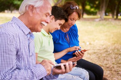 Abuelos-con-su-nieto-al-aire-libre-viendo-sus-telefonos-celulares